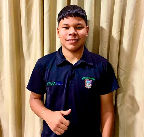 Joven sonriente con camiseta tipo polo negra con logotipos de SENATIC y un escudo institucional