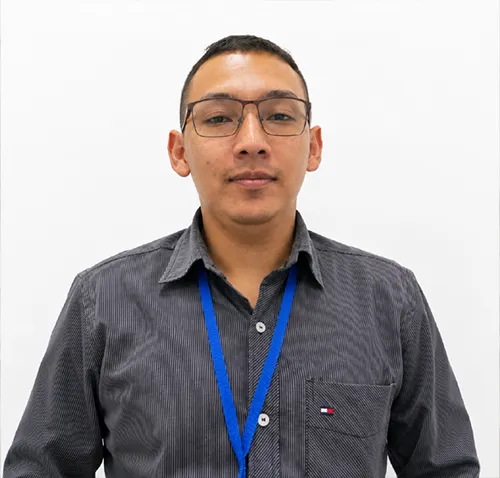Retrato de Carlos Alejandro Tiria Cabra, instructor de SENATIC, de pie frente a una cámara con fondo blanco