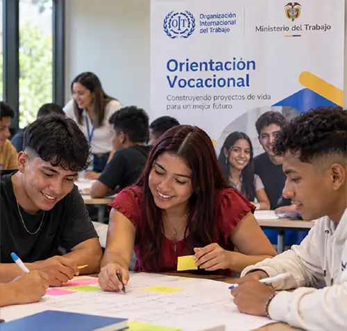 Cinco jóvenes participan en una actividad grupal de orientación vocacional alrededor de una mesa, escribiendo y organizando notas adhesivas mientras construyen de manera colaborativa sus proyectos de vida.