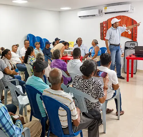 Grupo participa en una reunión comunitaria dentro de un salón iluminado